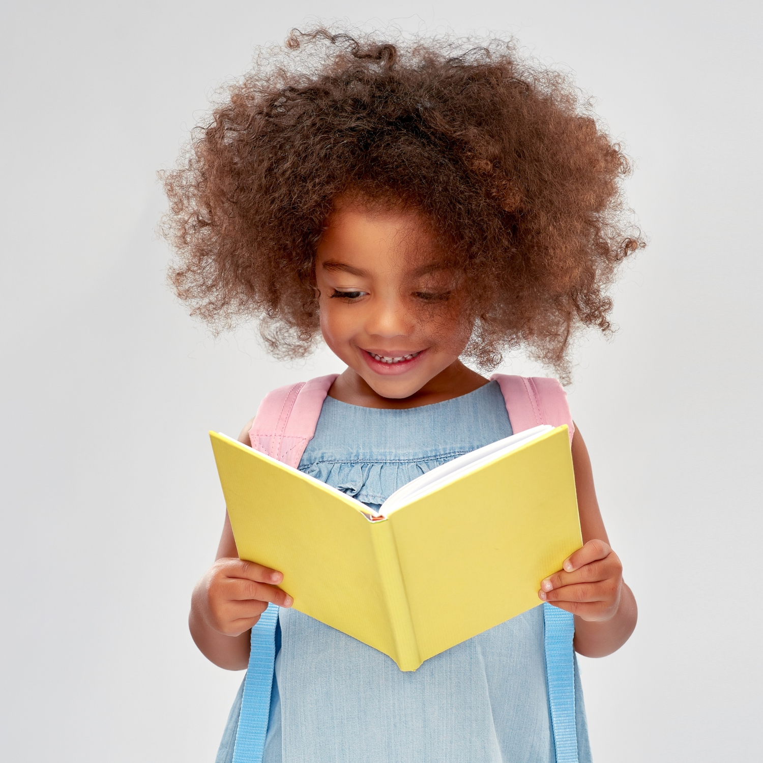 Young child reading a book, absorbed in learning at Sugarbees Academy's library